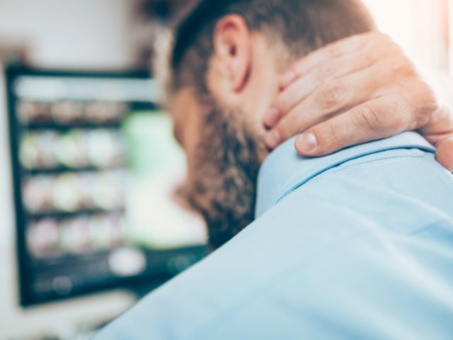 Office worker with neck pain from sitting at desk all day