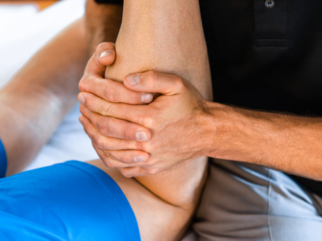 Sports physiotherapist massaging muscular strong man